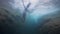 Underwater shot: Young tourist woman jumps into waterfall in slow motion.