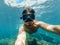 Underwater view of a diver man swimming in the turquoise sea under the surface with snorkelling mask taking a selfie