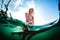 Underwater view of the happy woman sitting on the surfboard