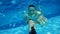 Underwater view of young man diving in swimming pool and smilling with open eyes. Active vacation