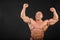 Undressed bodybuilder raises fists up