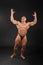 Undressed bodybuilder raises hands up