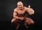 Undressed bodybuilder sits and thumbs up