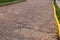 Undulating surface of a brick roadway patched with a variety of different brick styles, orange painted curb