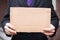 Unemployed businessman in an expensive suit with a blank cardboard sign on the street, close-up. Space for text