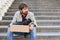 Unemployed man sitting on the stairs outdoors with a box of things. Fired a frustrated desperate man. Unemployment concept