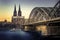 UNESCO Cathedral in Cologne Germany and Hohenzollern Bridge across Rhine River with Boat at Evening Sunset