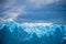 Uneven blue glacier against the background of a cloud in the sky. Shevelev.