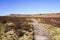 Uneven path crosses dry moorland and up to the top of Stanage Edge