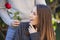 Unexpected moment in routine everyday life! Cropped photo of man`s hands holding a red rose. The happy woman is looking at the gif