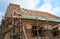 Unfinished brick house rooftop roofing construction attic trusses, wooden beams, eaves, timber, scaffolding.  House roof wooden