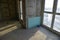 Unfinished interior of apartment under construction with gray concrete wall and double-glazed windows in residential building.