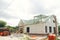 Unfinished modern farmhouse building. Wooden roof framing of mansard with dormer and aerated concrete block walls. Timber trusses