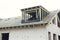 Unfinished modern farmhouse building. Wooden roof framing of mansard with dormer and vapor barrier on aerated concrete block walls