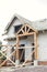 Unfinished modern farmhouse building. Wooden roof framing of mansard with dormer and vapor barrier on aerated concrete block walls