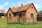 Unfinished red brick family house with worn down doors and faded window frames surrounded with rusted metal fence