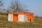 Unfinished red brick outdoor building without roof or windows surrounded with uncut grass and trees