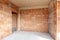 Unfinished room interior of building under construction. Brick red walls. New home