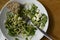 Unfinished salad on a wooden table. A cold appetizer of zucchini noodles, with fresh herbs and feta.On a white plate lies a piece