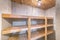 Unfinished small storage room with concrete walls and wooden shelves
