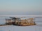 Unfinished structure on the frozen river on the background of winter city at sunset