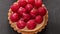 Unfinished to eat tartlet with custard and fresh ripe raspberries and brush for glazing over gray background. Flat lay