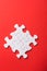 Unfinished white jigsaw puzzle pieces on red background