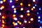Unfocused multicolored christmas lights with sparkle on dark background with bokeh effect