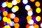 Unfocused multicolored shiny christmas lights on dark background with bokeh effect