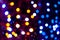 Unfocused multicolored shiny lights on dark background with bokeh effect for wallpaper