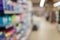 Unfocused shot of supermarket interior. Blurry hypermarket, mall or shopping center background. Rows and shelves with household ch