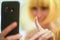 Unfocused soft blurred image in profile of a blonde girl using a smartphone