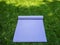 Unfolded purple yoga Mat or fitness Mat. Yoga Mat or Pilates in the shade on the green grass