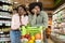 Unhappy African American Couple Standing With Shopping Cart In Supermarket