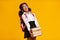 Unhappy afro schoolgirl carrying books over yellow background