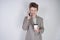 Unhappy angry teen in grey business suit stands with mobile phone and paper Cup of coffee on white background in Studio