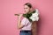 Unhappy attractive young woman with blonde hair wearing pink t-shirt holding white flowers bouquet