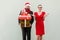 Unhappy bearded well dressed man holding many gift box and crying, women in black glasses and red dress looking at camera, toothy