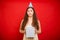 Unhappy birthday concept. Upset young woman in a festive cap with a gift in hands isolated on a red background