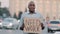 Unhappy black African American businessman holding cardboard Need Work emotional pointing on sign. Stressed frustrated