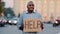 Unhappy black African American businessman holding cardboard with text help emotional pointing on sign. Stressed