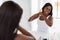 Unhappy Black Woman Untangling Her Hair With Bamboo Brush In Bathroom