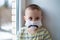 Unhappy boy in medicine mask, closeup portrait, quarantine at home, virus protection