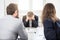 Unhappy businessman with his colleagues sitting at the desk on a meeting in the office