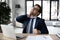 Unhappy businessman massaging stiff neck muscles, sitting at work desk