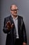 Unhappy busuness man in black suit and glasses showing the palm the stop sign on grey background. Closeup