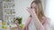 Unhappy Caucasian girl closing nose with fingers to drink green healthful cocktail. Portrait of slender young blond