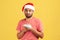 Unhappy confused bearded man in santa claus hat holding dollars in hands, greedy to buy holiday gifts