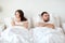 Unhappy couple having conflict in bed at home