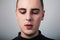 Unhappy crying young man with dropping tears on the face. Closeup studio portrait on grey background.